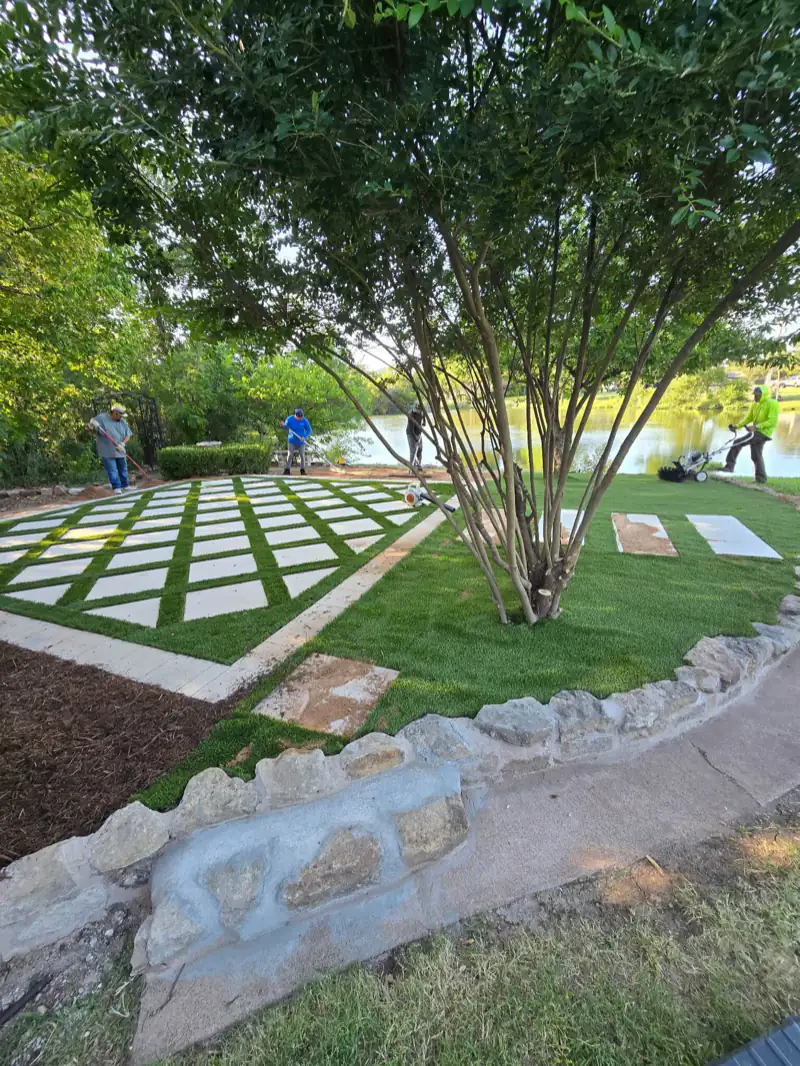 Stepping-stone pavers set in fresh turf beneath a live oak, edged with a stone border